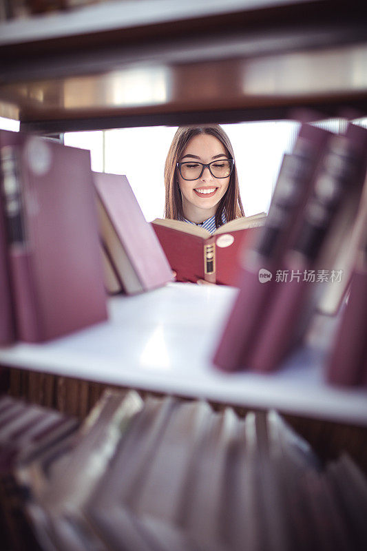 图书馆/书店里的漂亮女孩。放着旧书的书架